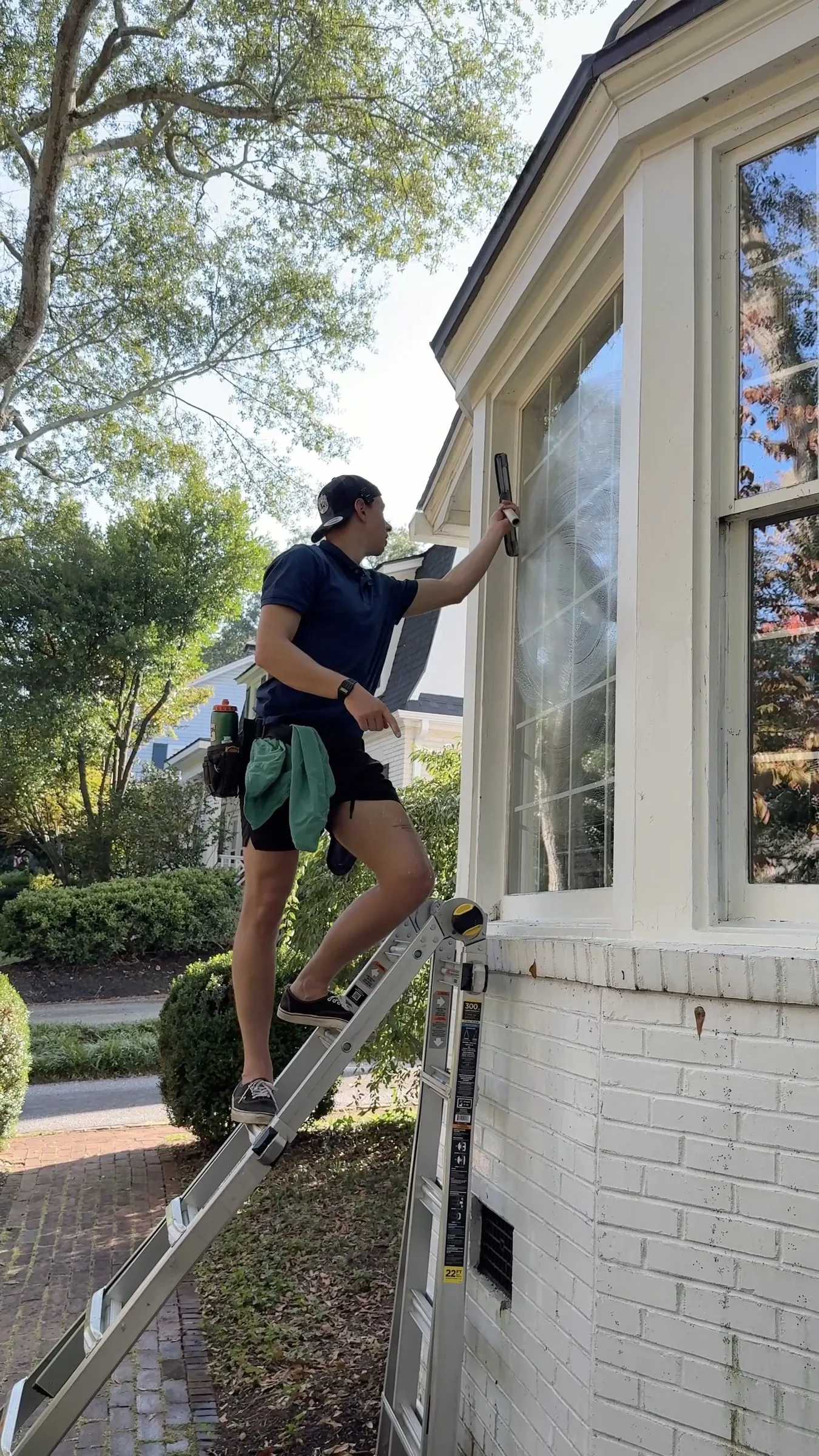 Technician on an extension ladder cleaning a bay window