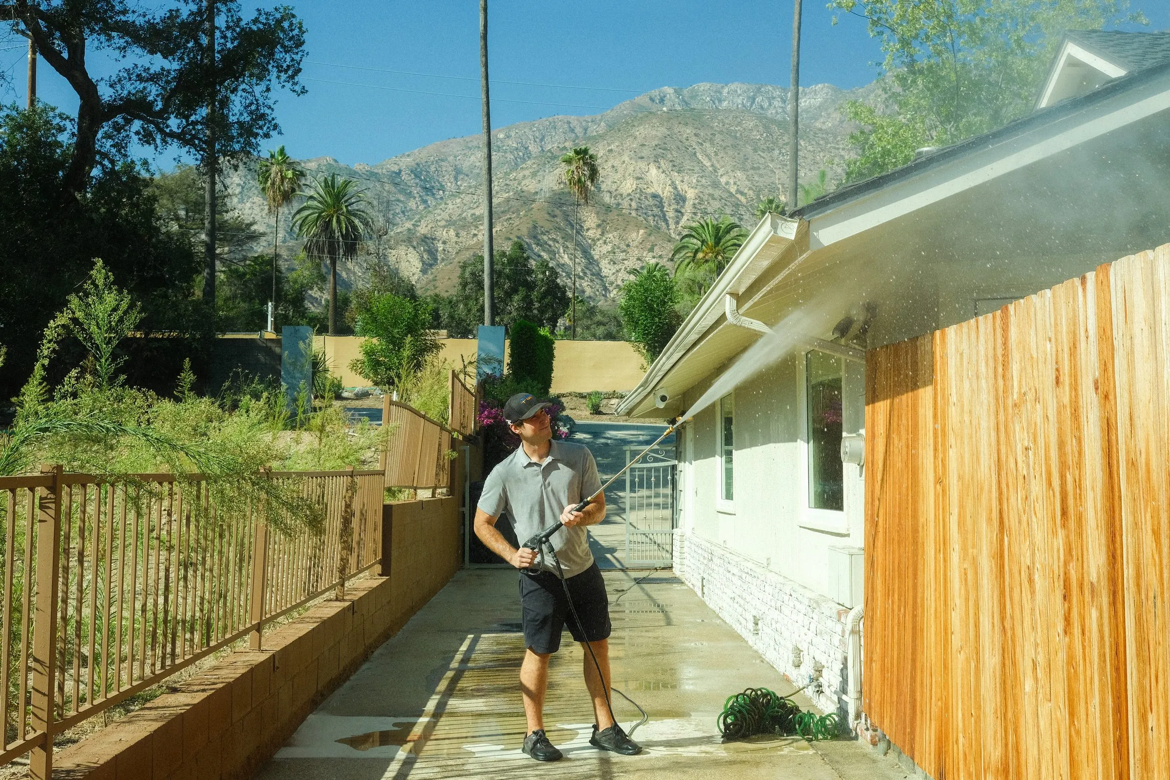 Elliot washing the eaves of a ranch house with mountains behind